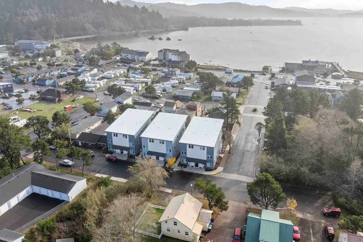 A broad waterfront view with residential buildings, roadways winding through green spaces, and the gentle curve of the shore. The setting suggests opportunities for morning walks, sunset views, and community festivals along the water’s edge.