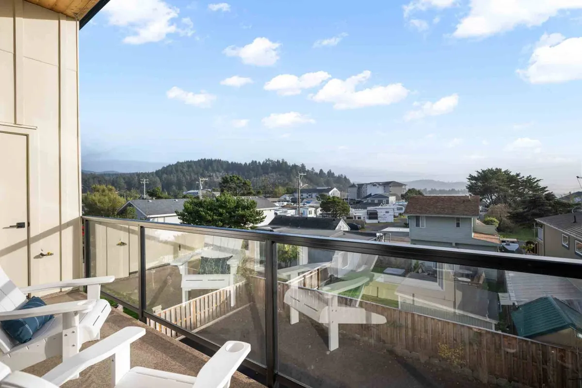 An exterior view of a private balcony featuring Adirondack chairs and a tranquil vista of distant hills. The setup is perfect for enjoying morning coffee, reading, or taking in the sunset—showcasing the direct connection between indoor social spaces and the outdoor retreat.