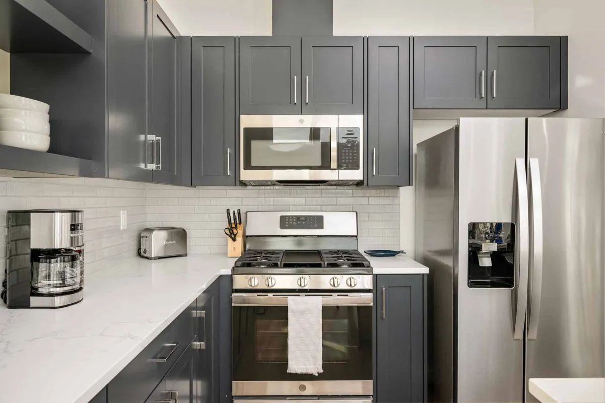 A contemporary kitchen featuring stainless steel appliances, a marble countertop, and sleek dark cabinetry. The space is well-lit and designed for both functionality and style, creating an inviting atmosphere for cooking and entertaining.