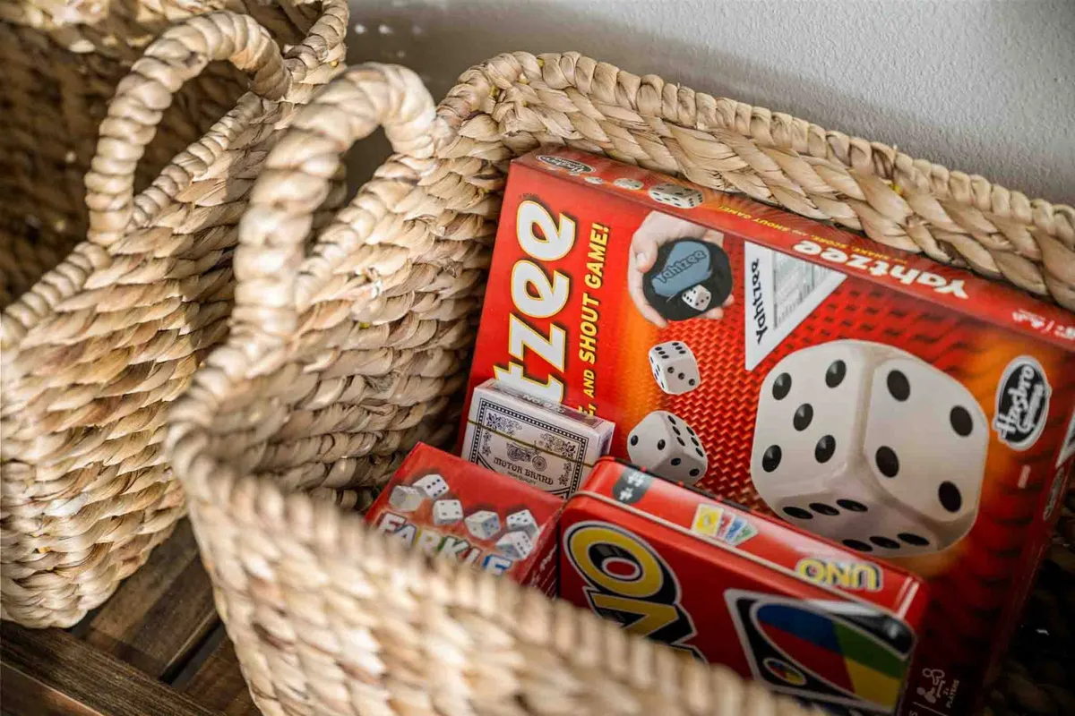 A close-up of board games neatly arranged in woven baskets, highlighting playful, lighthearted moments. The setting feels casual and inviting, emphasizing togetherness and shared fun.