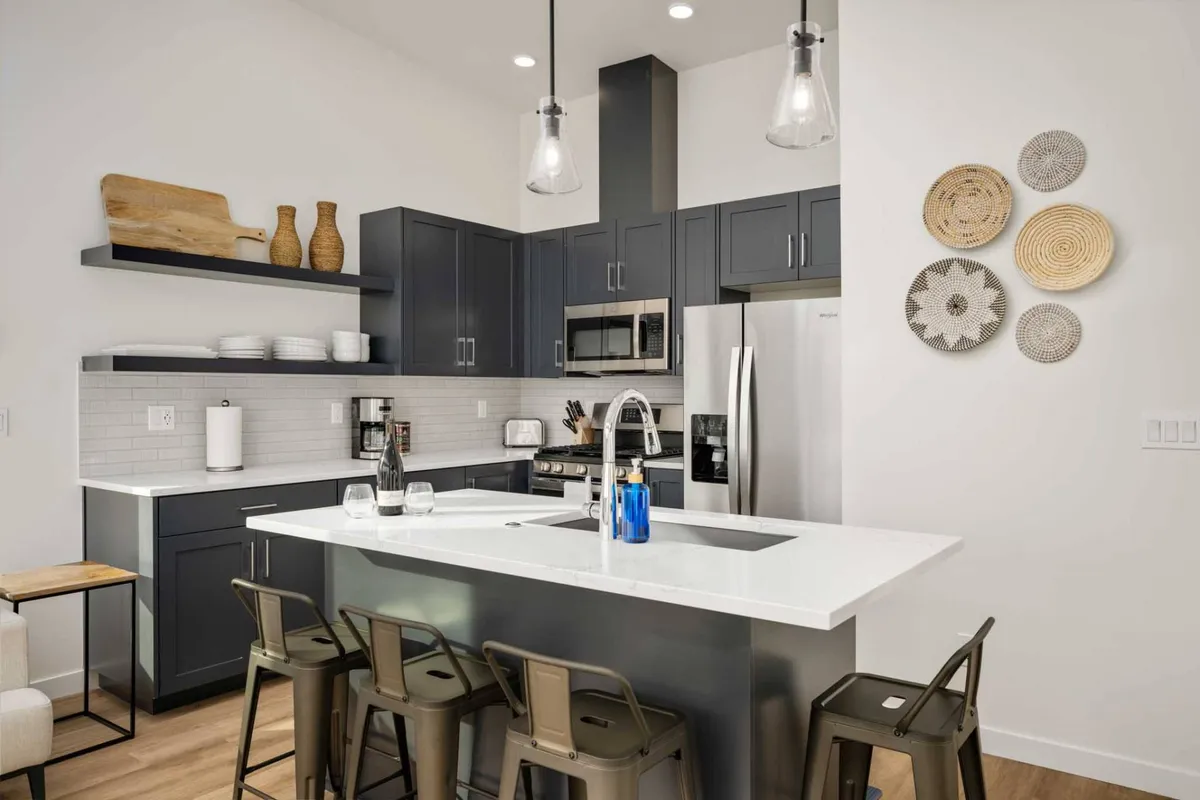 A stylish kitchen island with metal stools is complemented by decorative plates on the wall, offering a welcoming space for cooking, entertaining, and casual family meals. The scene highlights both functionality and social gathering aspects.